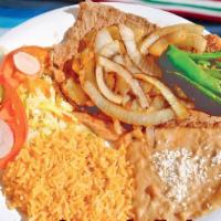 Bistec Encebollado · Steak topped grilled onions. Served with rice, beans, and salad.