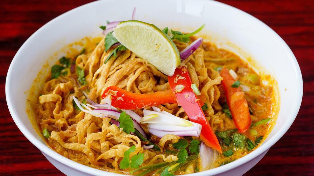 Chaing Mai Noodles (Kao Soy Thai) · Egg noodles served in light yellow curry soup with chicken, pickled mustard greens, and red onions topped with fried egg noodle.
