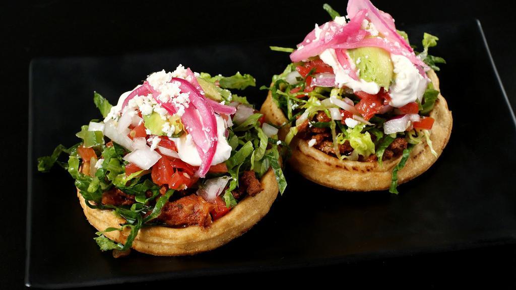 Sopes · Your choice of protein on top of thick fried masa with lettuce, pickled red onion, salsa, cheese, crema, refried black beans, and pico de gallo.