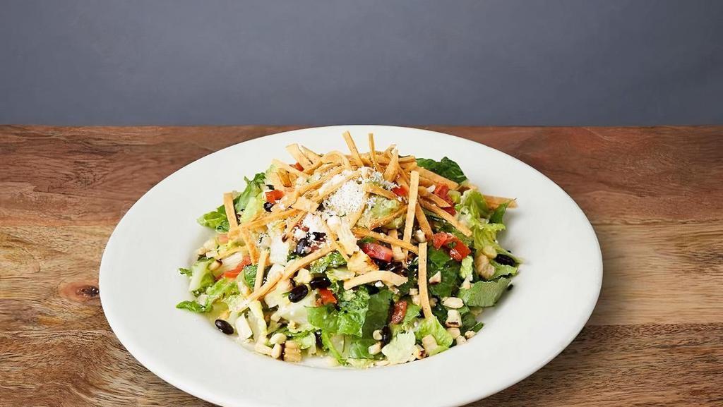 CORN & BLACK BEAN TACO SALAD · Romaine lettuce, grilled corn, black beans, and pico de gallo tossed in lime vinaigrette; topped with guacamole, tortilla strips, and a touch of cotija cheese
