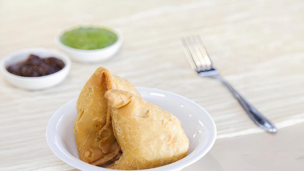 Samosa (2 pcs) · Deep-fried triangular pastry stuffed with mildly spiced potatoes and green peas. Served with mint & tamarind chutney. Vegan.