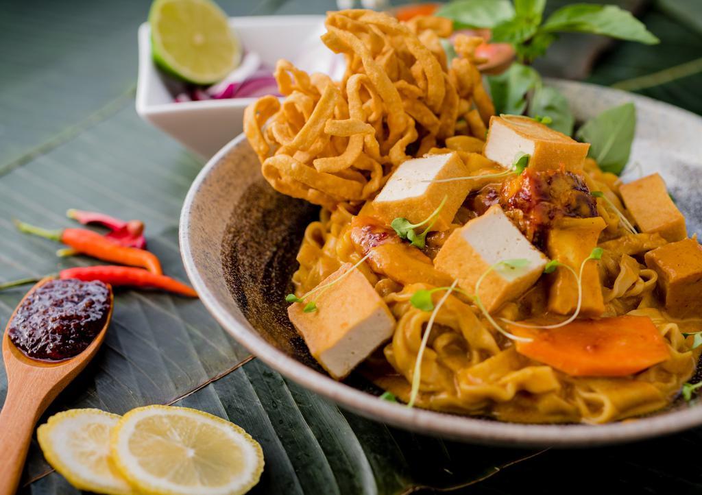 Curry Noodles (Khao Soi) · *Spicy. Egg noodles in a coconut milk enriched curry with Thai chili paste, garnished with red onions, fried onions, and lime.