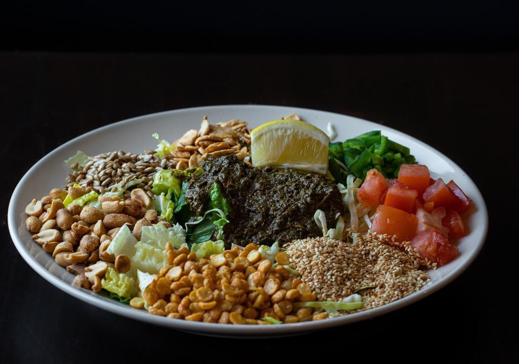 Tea Leaf Salad · A mix of Burmese tea leaves, fried garlic, yellow beans, peanuts, sesame seeds, sunflower seeds, tomatoes and jalapeños over a bed of romaine lettuce and a fresh squeeze of lemon.