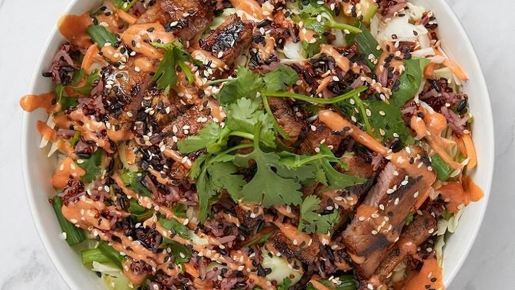 Korean Bbq Steak Bowl · Seared steak, black rice & red quinoa,  cabbage, cucumbers, carrots, green onions, cilantro, sesame seeds, sesame dressing and Gochujang chile sauce.