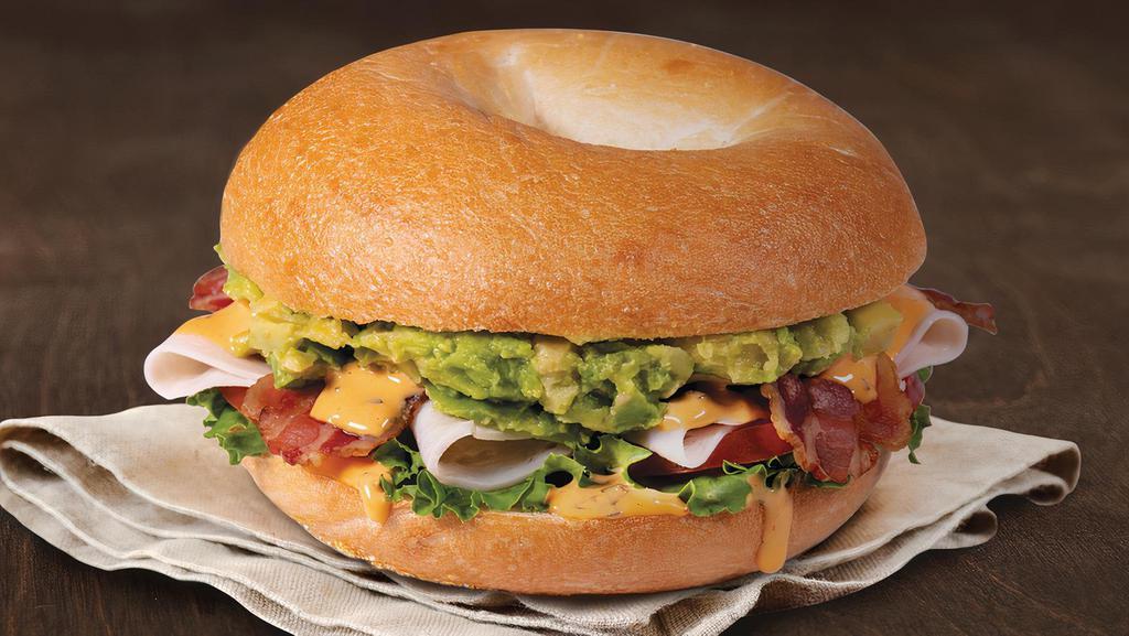 Turkey, Bacon & Avocado Sandwich · Turkey, bacon, creamy avocado, lettuce, tomato, and roasted tomato spread on a plain bagel.