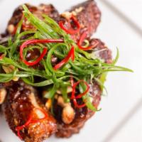 Fried Pork Ribs · Baby back ribs smothered in a sweet and spicy sauce, peanuts, fresno, scallions.