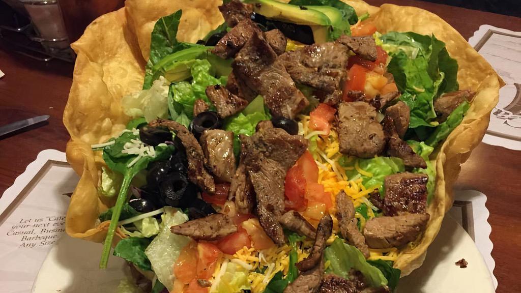 Carne Asada Taco Salad · Seasoned carne asada with a crisp tostada shell filled with fresh greens, avocado, tomatoes, onions, olives, jack and cheddar cheese. Served with sour cream and salsa (no bread).