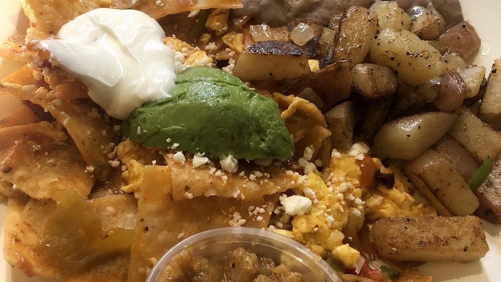 Chilaquiles · Crispy corn tortilla chips cooked with two srambled eggs, seasoned ground beef, caliente ranchero sauce and topped with feta cheese, avocado, and sour cream.  Served with papas and beans.