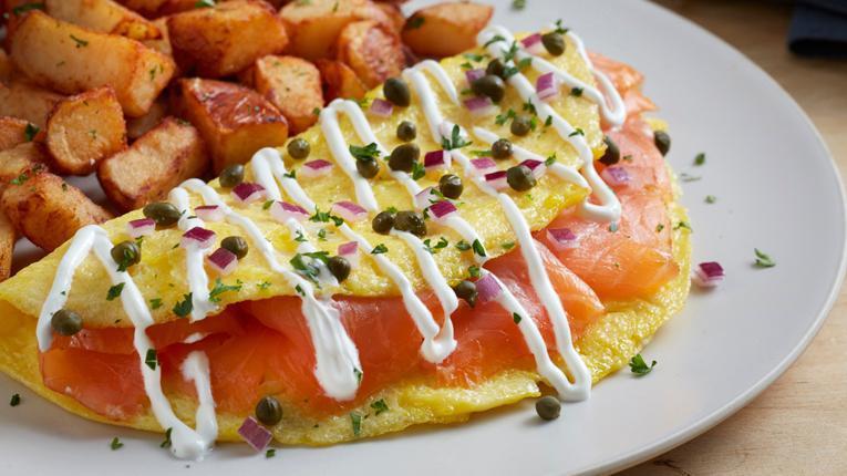 Smoked Salmon Omelet · Three eggs, cold-smoked Atlantic salmon, diced red onions, capers and sour cream sauce. Served with roasted potatoes. (560 cal) .