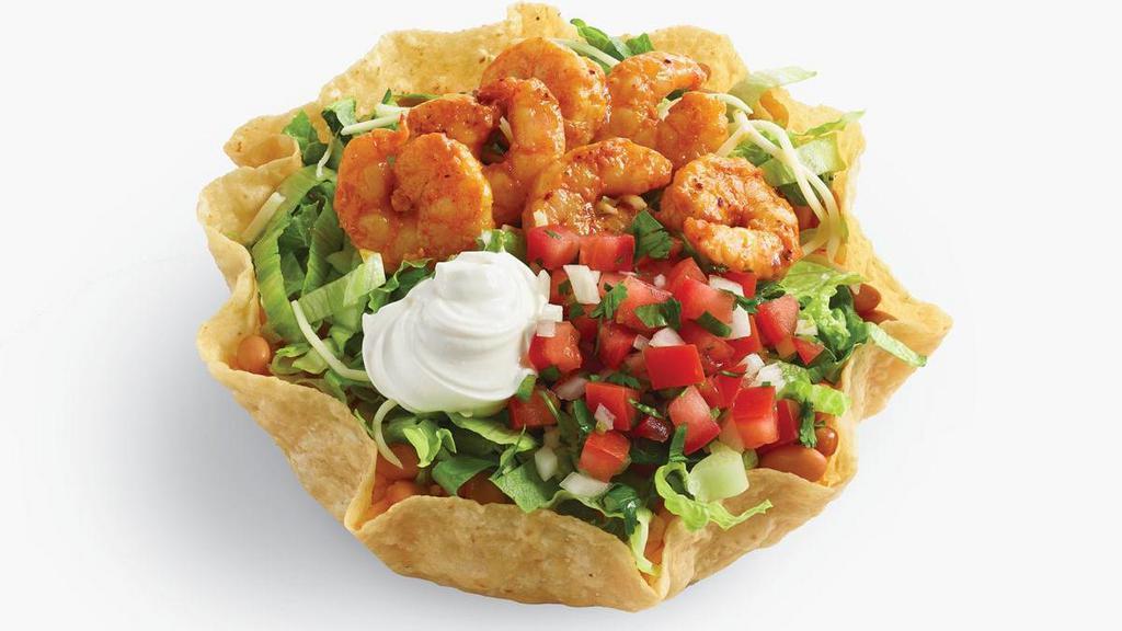 Baja Shrimp Tostada Salad · Savor tender shrimp marinated in garlic and spices, shredded lettuce, pinto beans, rice, shredded jack cheese, sour cream and pico de gallo salsa in a crisp flour tostada shell. Served with creamy cilantro dressing.