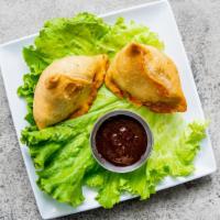 Vegetable Samosa · Two triangular fried pastries stuffed with peas and potatoes.