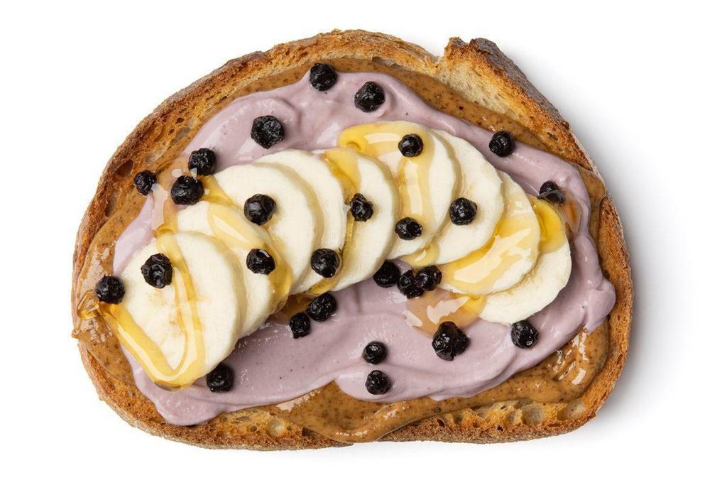 Acai Almond Butter Toast · Savory Almond Butter with a layer of Acai Greek Yogurt topped with sliced Bananas, dried Blueberries and drizzled with Honey on a thick slice of sourdough toast.. Almond Butter, Banana, Blueberries, Yogurt with Acai, Honey