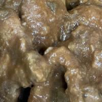 Smothered Pork Chops · Three fried pork chops smothered in dark savory gravy served over white rice. Two sides, cor...