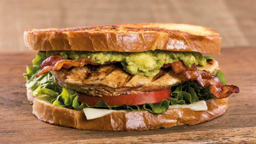Sourdough Chicken Avocado Sandwich · Stacked high with grilled all-natural chicken breast, thick hickory-smoked bacon, hand-smashed Hass avocado, tomato, cheese, green leaf lettuce, and mayonnaise on locally-baked grilled garlic sourdough bread. It’s not a sandwich, it’s a farm fresh flavor extravaganza.