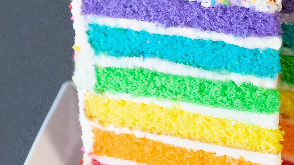 Rainbow Cake Slice · Six layers of rainbow-colored vanilla cake filled and iced with sweet vanilla buttercream icing, covered in rainbow sprinkles.