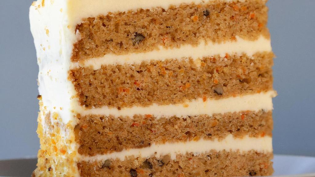 Carrot Cake Slice · Our classic carrot cake contains chunks of pineapple, chopped walnuts, coconut shavings, and golden raisins. Filled and topped with a sweet cream cheese icing and carrot cake crumbs.
