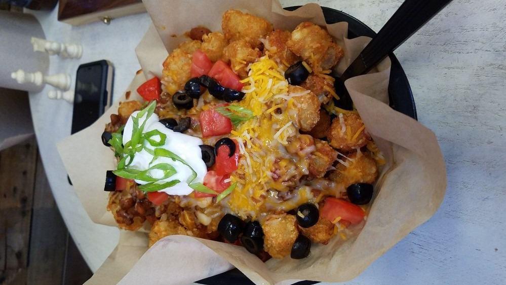 Spudchos Porkytizers · This is our spin on nachos! Your choice of Fries, Tater Tots, or Chips, smothered with our chili beans, shredded cheese, black olives, tomatoes, sour cream, and green onion.