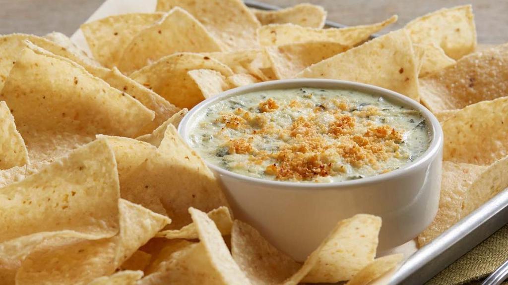Spinach And Artichoke Dip · A creamy blend of spinach, artichokes, cream cheese and parmesan cheese.  Served hot with crispy corn tortilla chips.