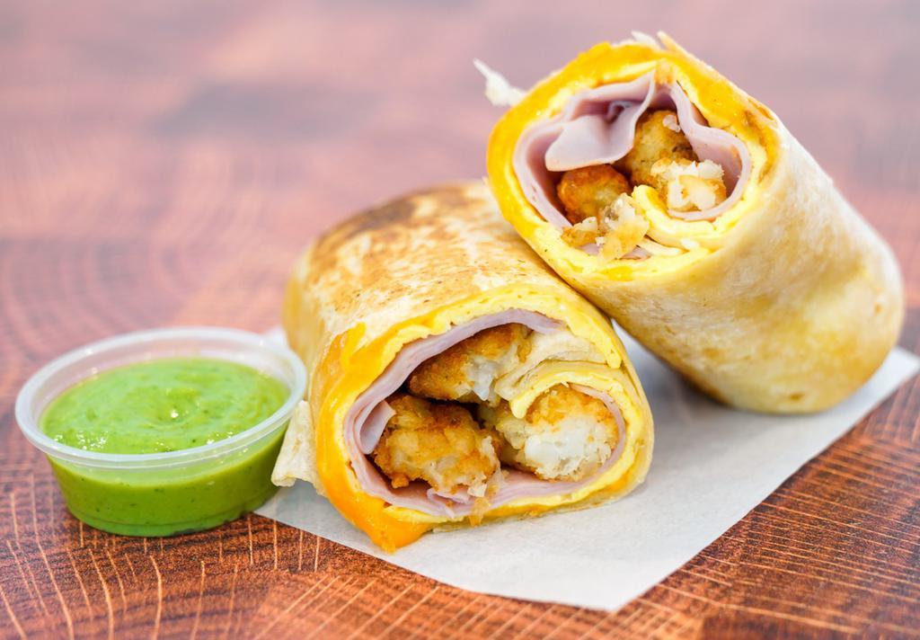 Ham, Egg, & Cheddar Breakfast Burrito · 3 fresh cracked, cage-free scrambled eggs, melted Cheddar cheese, sliced ham, and crispy potato tots wrapped in a toasted 12” flour tortilla. Comes with avocado salsa verde side.