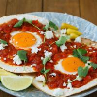 Huevos Rancheros / Ranchero Eggs · Tortilla frita sobre huevos en salsa roja, servida con arroz y frijoles. / Fried tortilla on...