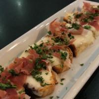 Prosciutto Crostini · Toasted housemade bread with melted mozzarella and topped with prosciutto.