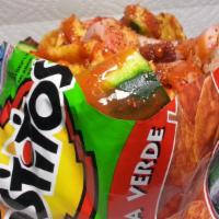Tostiloco · Container filled with Tostitos topped with fresh cucumbers, pork cueritos, fresh mango piece...