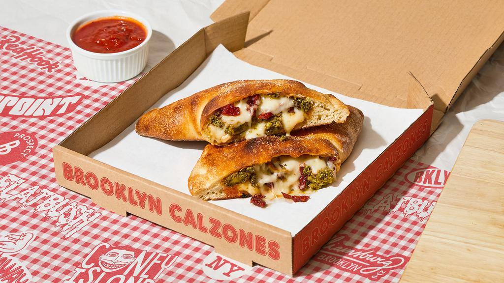 The Heights Calzone · Calzone with juicy pesto chicken, tomato, melted parmesan and mozzarella, and a side of marinara.