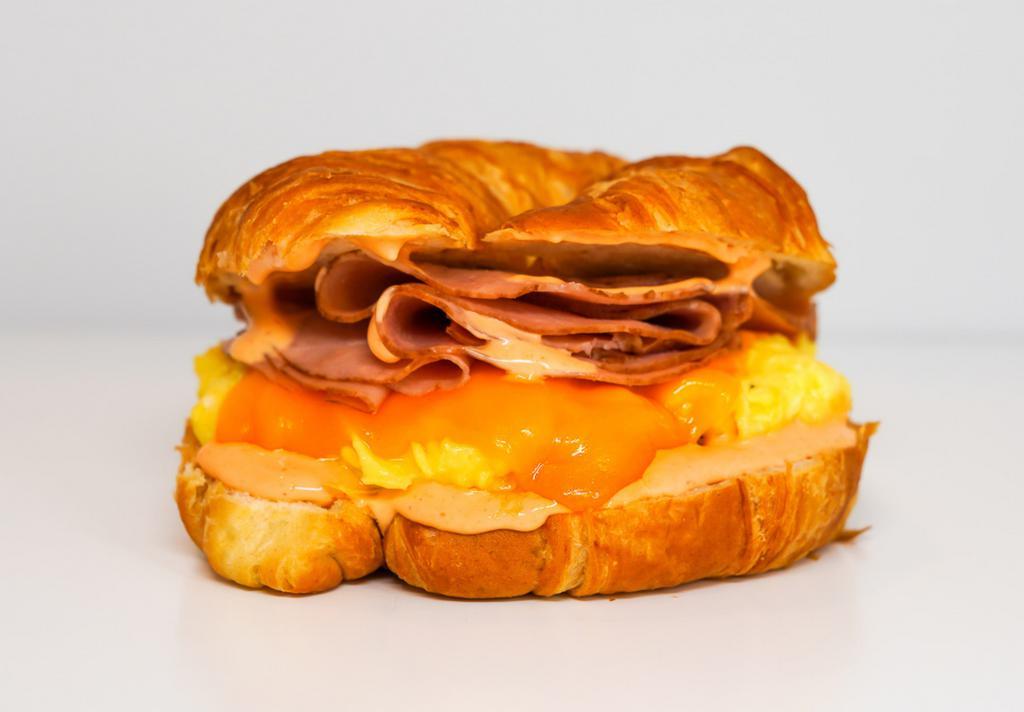 Croissant, Ham, Egg, & Cheese Sandwich · 2 scrambled eggs, melted cheese, sliced ham, and Sriracha aioli on a warm croissant.