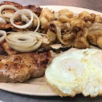 Chuletas De Puerco · Pork Chops cooked with grilled onion.  Accompanied with home made potatoes and two eggs.