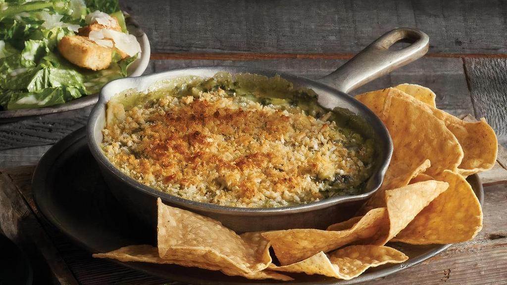 Baked Spinach & Artichoke Dip · Parmesan, Jack and cream cheeses beneath a bread crumb topping, served with tortilla chips.