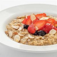 Steel Cut Oats · A bowl of steel cut oatmeal served with strawberries, blueberries, sliced almonds and organi...
