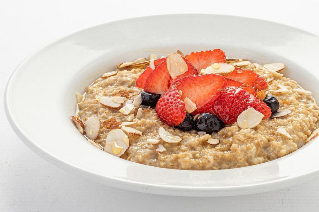 Steel Cut Oats · A bowl of steel cut oatmeal served with strawberries, blueberries, sliced almonds and organic agave syrup.