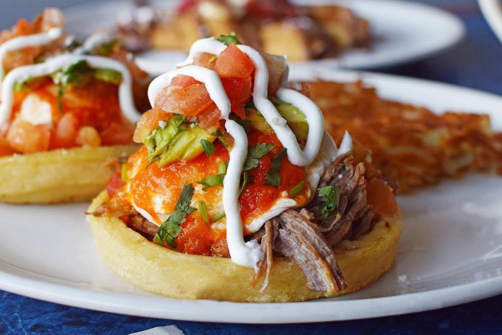 Sope Benedict · Two extra thick and crispy corn tortillas filled with shredded beef and topped with poached eggs, homemade ranchero sauce, sliced avocado, fresh salsa, cotija cheese and sour cream.
