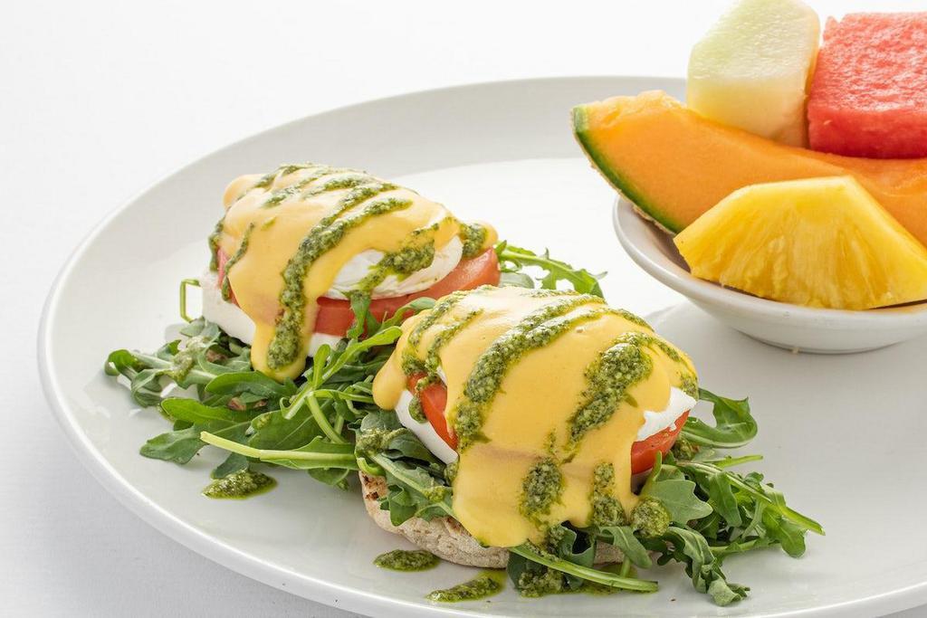 Caprese Benedict · A toasted English muffin topped with arugula, fresh mozzarella cheese, sliced tomato, poached eggs, hollandaise sauce and pesto basil drizzle.