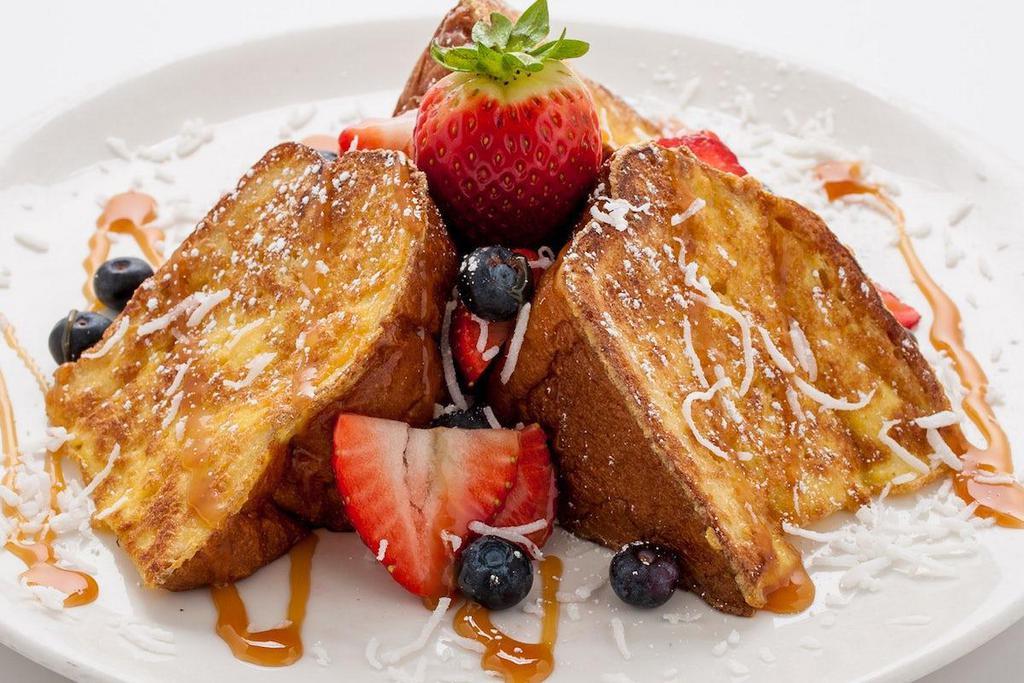 Tiki Toast · Three extra thick slices of sweet Hawaiian bread, grilled to a golden brown and topped with strawberries, blueberries, shredded coconut, caramel drizzle and powdered sugar.