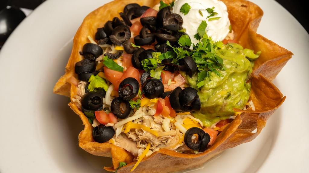 Taco Salad · Meat, lettuce, tomatoes, cilantro, and cheese topped with bits of tortilla chips, black olives, sour cream, and guacamole.
