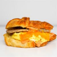 Sausage, Egg And Cheddar Croissant Sandwich · 2 scrambled eggs, melted Cheddar cheese, breakfast sausage, and Sriracha aioli on a  warm cr...