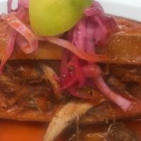 Torta Ahogada · Refried beans, carnitas, and pickled onion covered with tomato sauce and spicy sauce on the ...