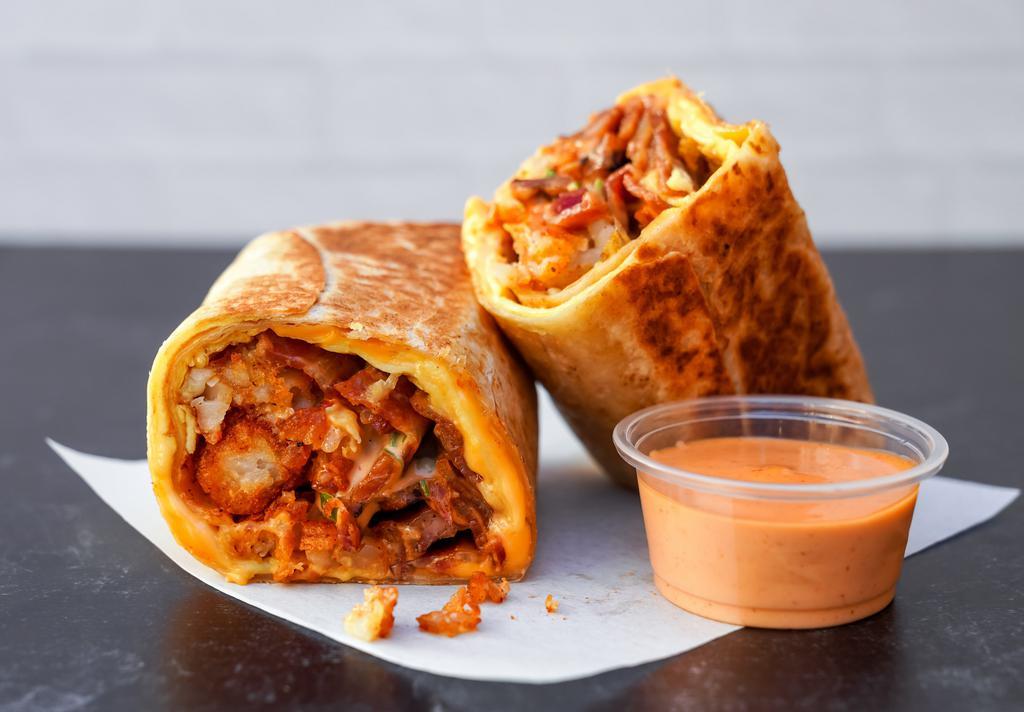 The One Breakfast Burrito · 3 slices of crispy thick-cut bacon, sauteed chicken apple sausage, triple egg omelet, chili aioli, gooey American cheese, scallions, and fried potato tots seasoned with Nashville spices all encased in a toasted flour tortilla.