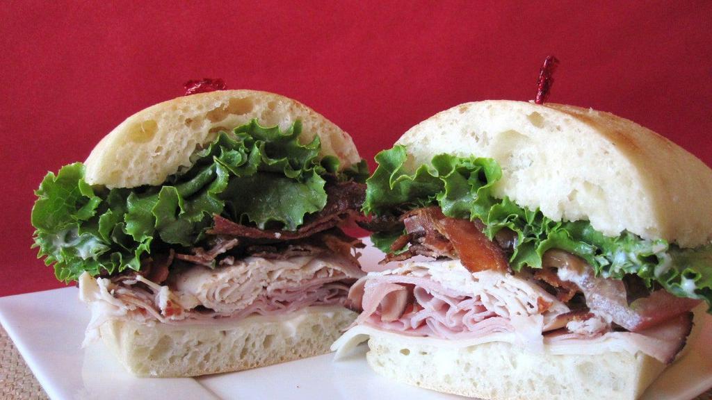 Club Deluxe · Roasted turkey, black forest ham, bacon, baby Swiss cheese, lettuce, tomato and mayo on an onion dill roll.