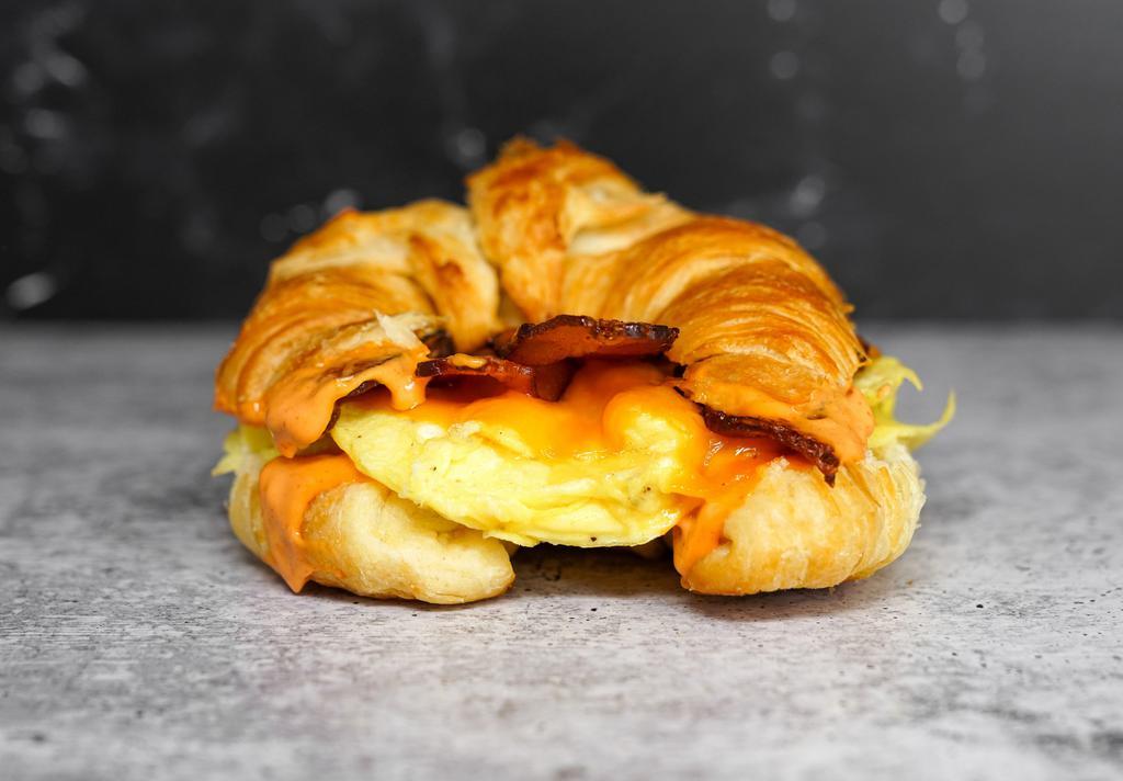 Croissant, Bacon, Egg, & Cheddar Sandwich · 2 scrambled eggs, melted Cheddar cheese, smoked bacon, and Sriracha aioli on a warm croissant.