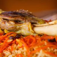 Lamb Qhabuli Palaw · large lamb shank cooked in brown rice topped with raisins and julienne carrots.
