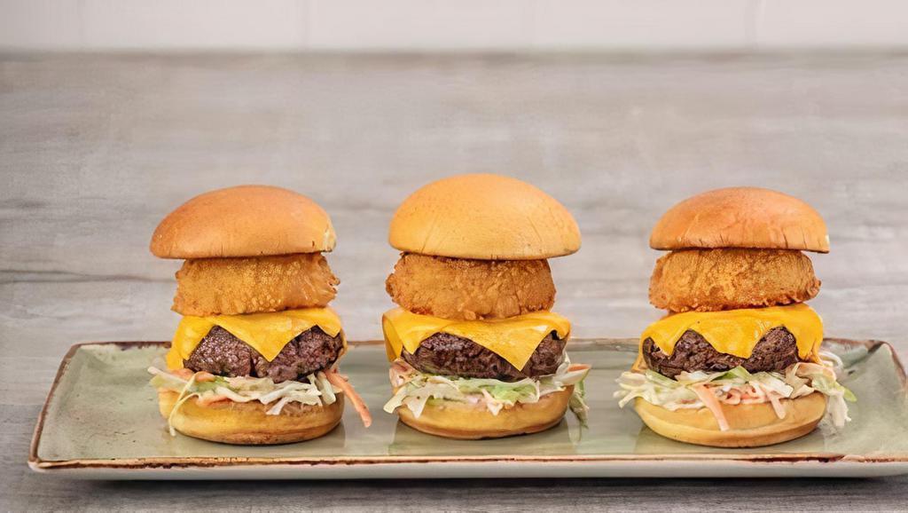 All American Sliders · Three mini-burgers with melted American cheese, crispy onion ring and creamy coleslaw on a toasted brioche bun.