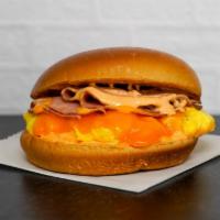 Brioche, Ham, Egg, & Cheddar Sandwich · 2 scrambled eggs, melted Cheddar cheese, sliced ham, and Sriracha aioli on a warm brioche bun.