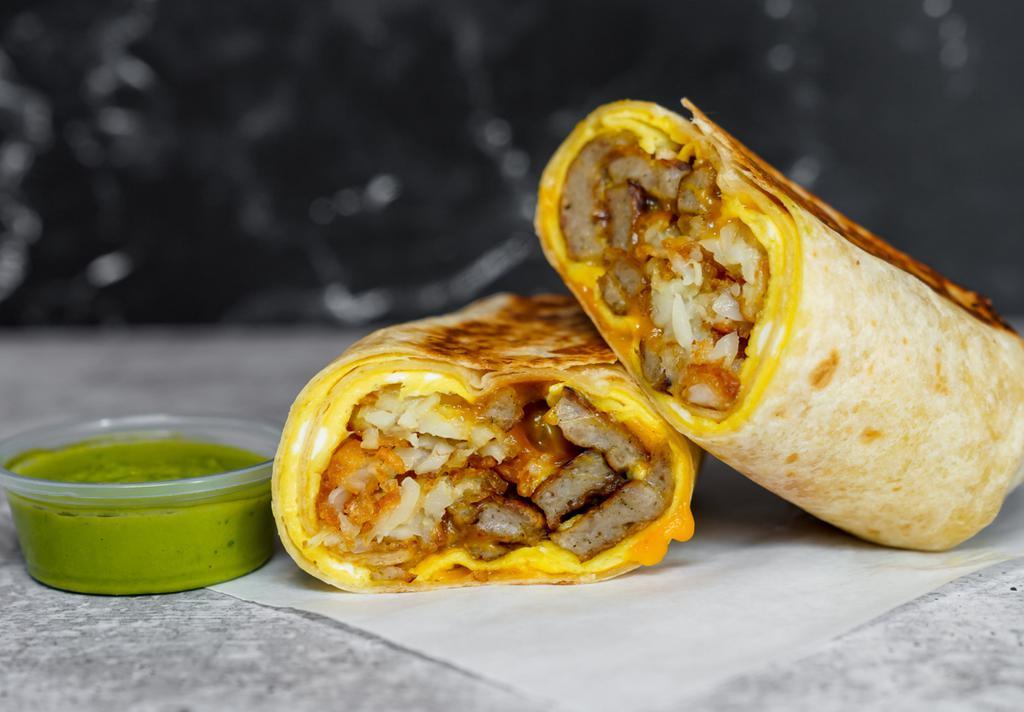 Sausage, Egg, & Cheddar Breakfast Burrito · 3 fresh cracked, cage-free scrambled eggs, melted Cheddar cheese, seared pork sausage patties, and crispy potato tots wrapped in a toasted 12” flour tortilla. Comes with avocado salsa verde side.