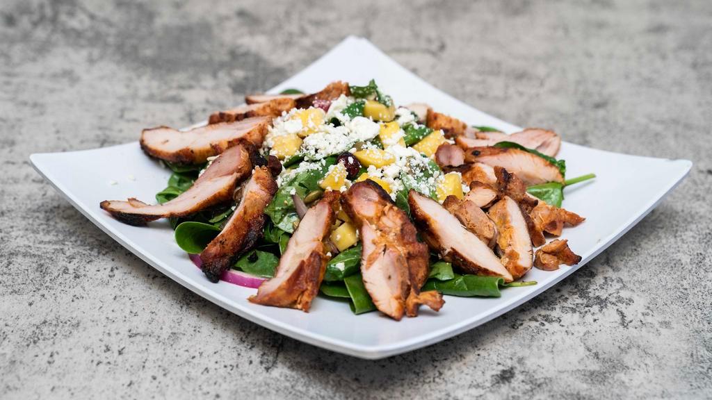 Mango Salad · Fresh cubed mango, red onion, baby spinach, and cranberries, tossed in balsamic vinaigrette and topped with goat cheese and toasted pepitas.