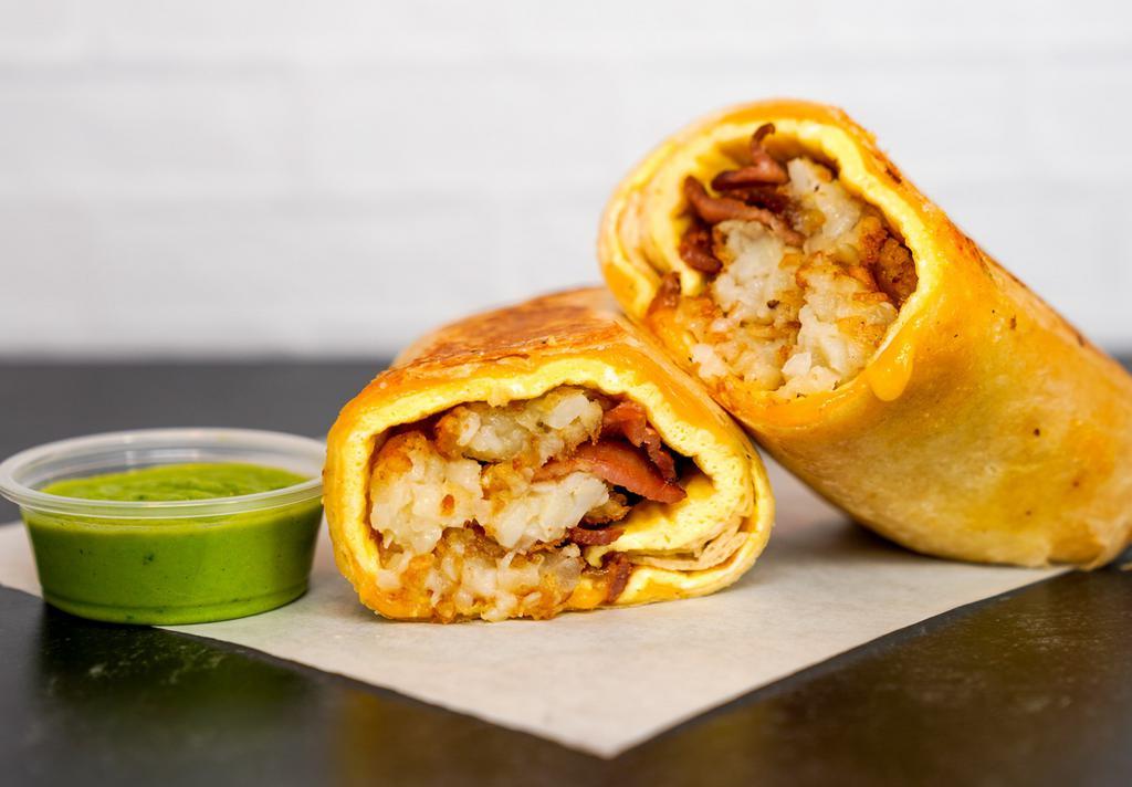 Bacon, Egg, & Cheddar Breakfast Burrito · 3 fresh cracked, cage-free scrambled eggs, melted Cheddar cheese, smokey bacon, and crispy potato tots wrapped in a toasted 12” flour tortilla. Comes with avocado salsa verde side.