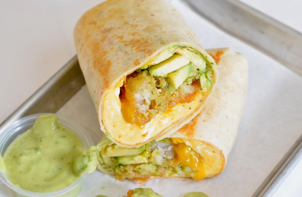 Avocado, Egg, And Cheddar Breakfast Burrito · 3 fresh cracked, cage-free scrambled eggs, melted Cheddar cheese, avocado salsa verde, fresh avocado, and crispy potato tots wrapped in a toasted 12” flour tortilla. Comes with avocado salsa verde side