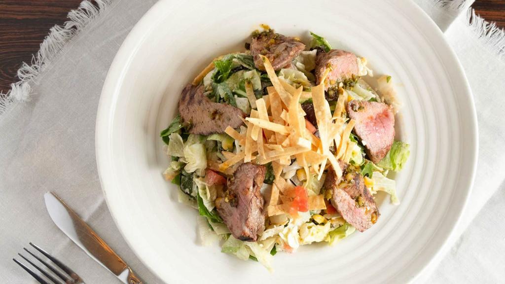 Tri Tip Salad · Tri tip, crisp greens, spicy cilantro mayo dressing, chipotle chimichurri sauce, corn, black beans, queso fresco, tortilla strips.
