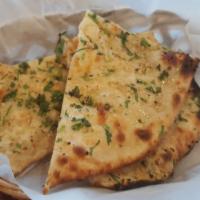 Garlic Naan · Indian style garlic bread baked on the sides of our tandoori oven.